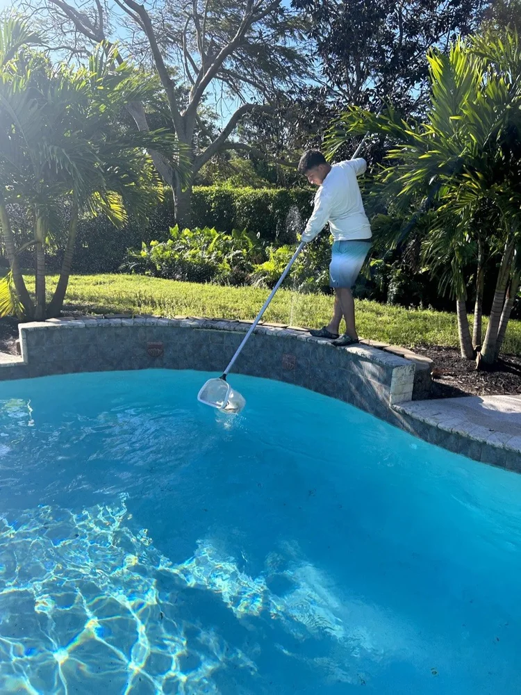 Get Wet Pools technician cleaning a backyard swimming pool