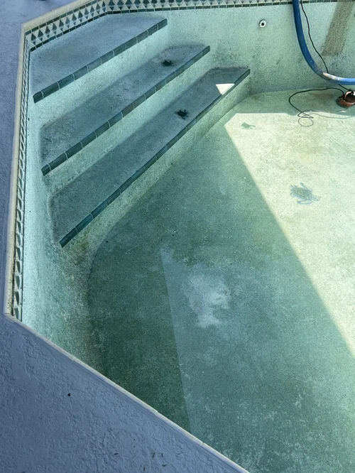 Drained pool steps and existing surface before resurfacing in The Heights, Jupiter.