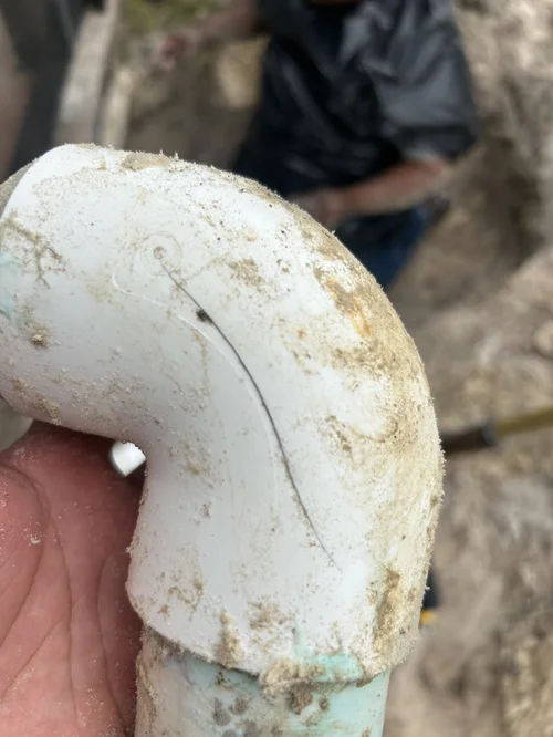 Close view of a cracked PVC elbow removed during a Jupiter Farms skimmer leak repair.