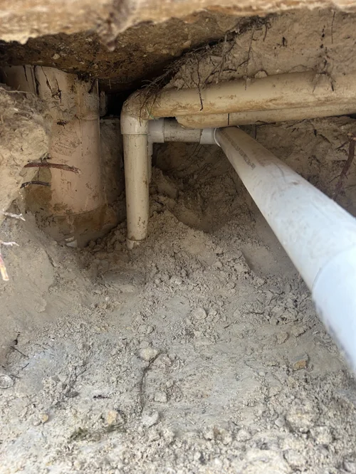 Close view of exposed skimmer pipe connections beneath a Jupiter Farms pool deck.