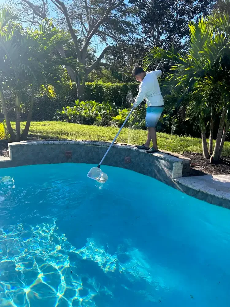 Get Wet Pools technician cleaning a backyard swimming pool
