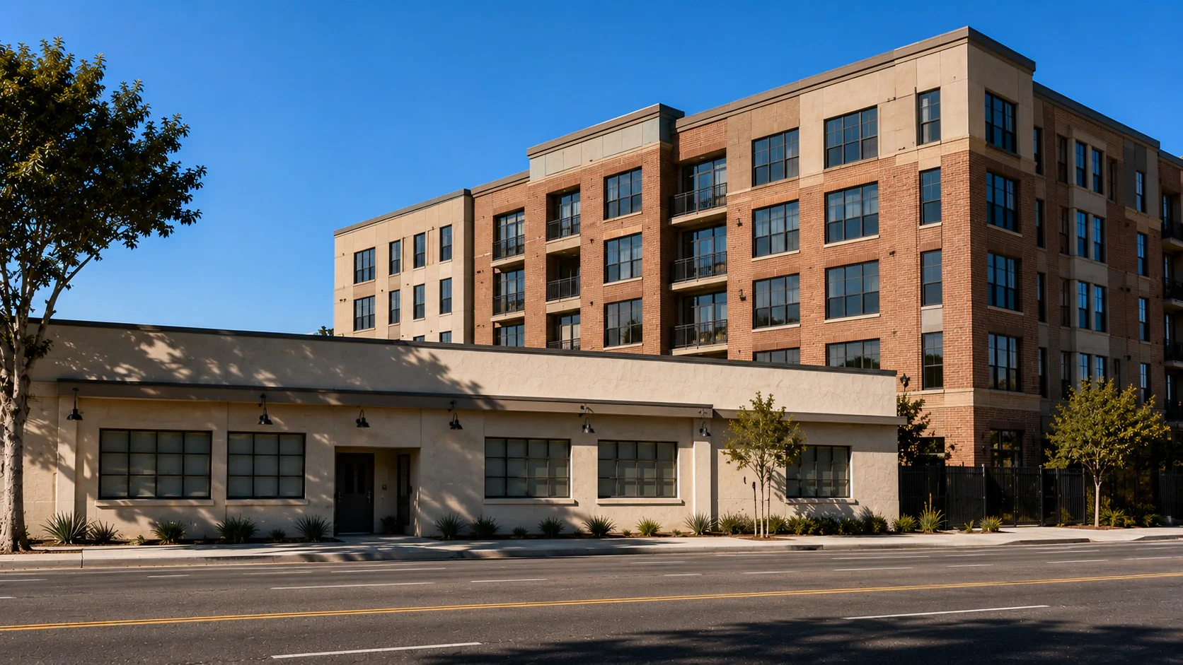 An older single-storey commercial building on a North Hollywood corridor with a five-storey mixed-use building rising directly behind it, the height difference dominating the frame.