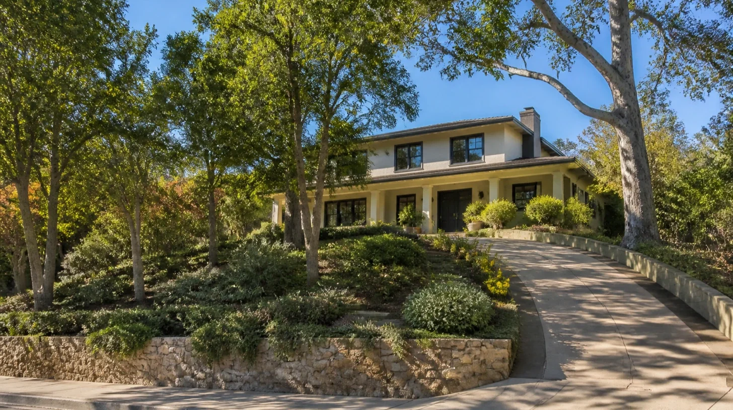 A larger two-storey Encino home on rising ground south of Ventura Boulevard, a stone retaining wall holding the grade change and a driveway climbing to the entrance.