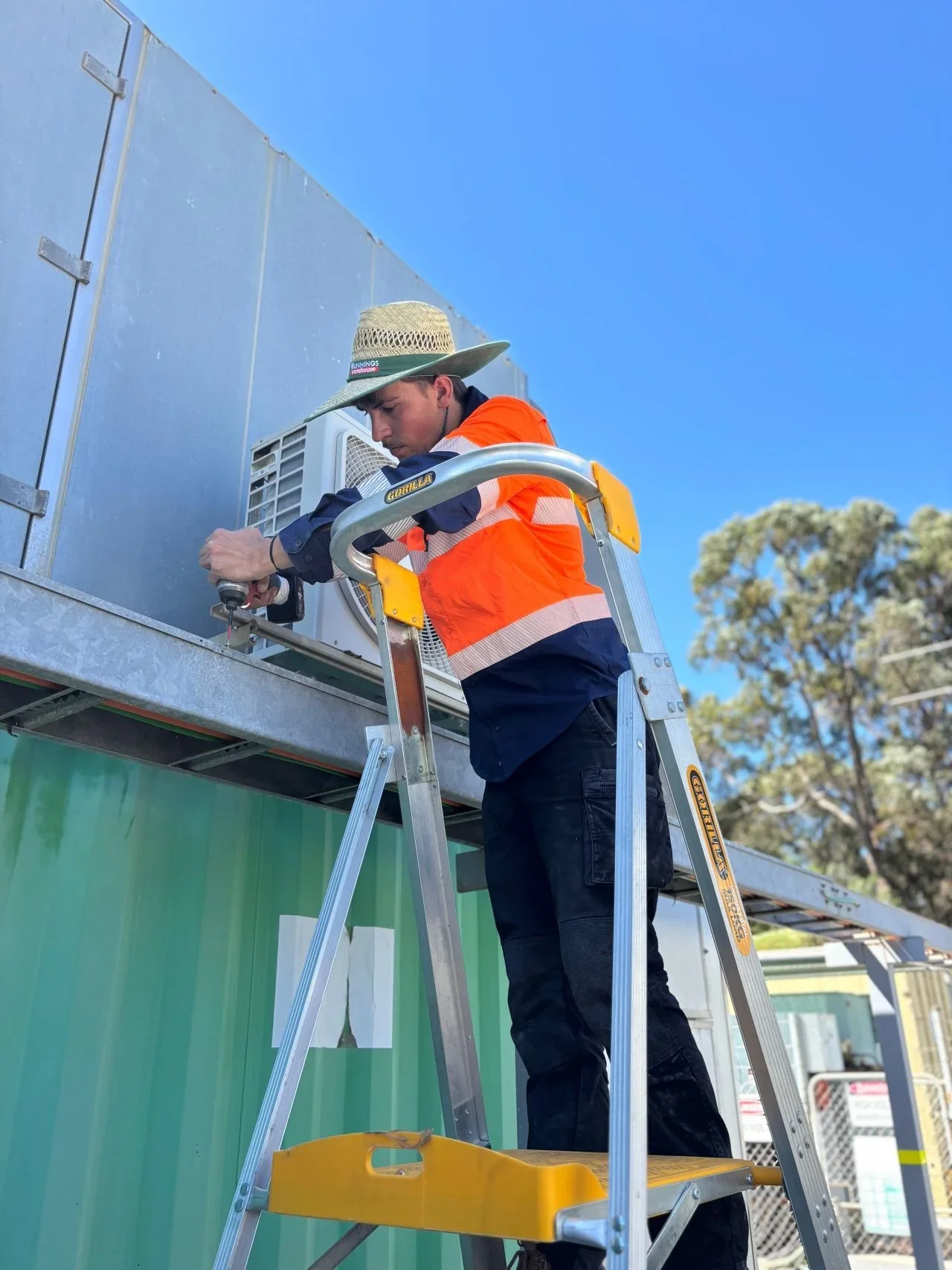 BESS air conditioning technician installing outdoor split system unit