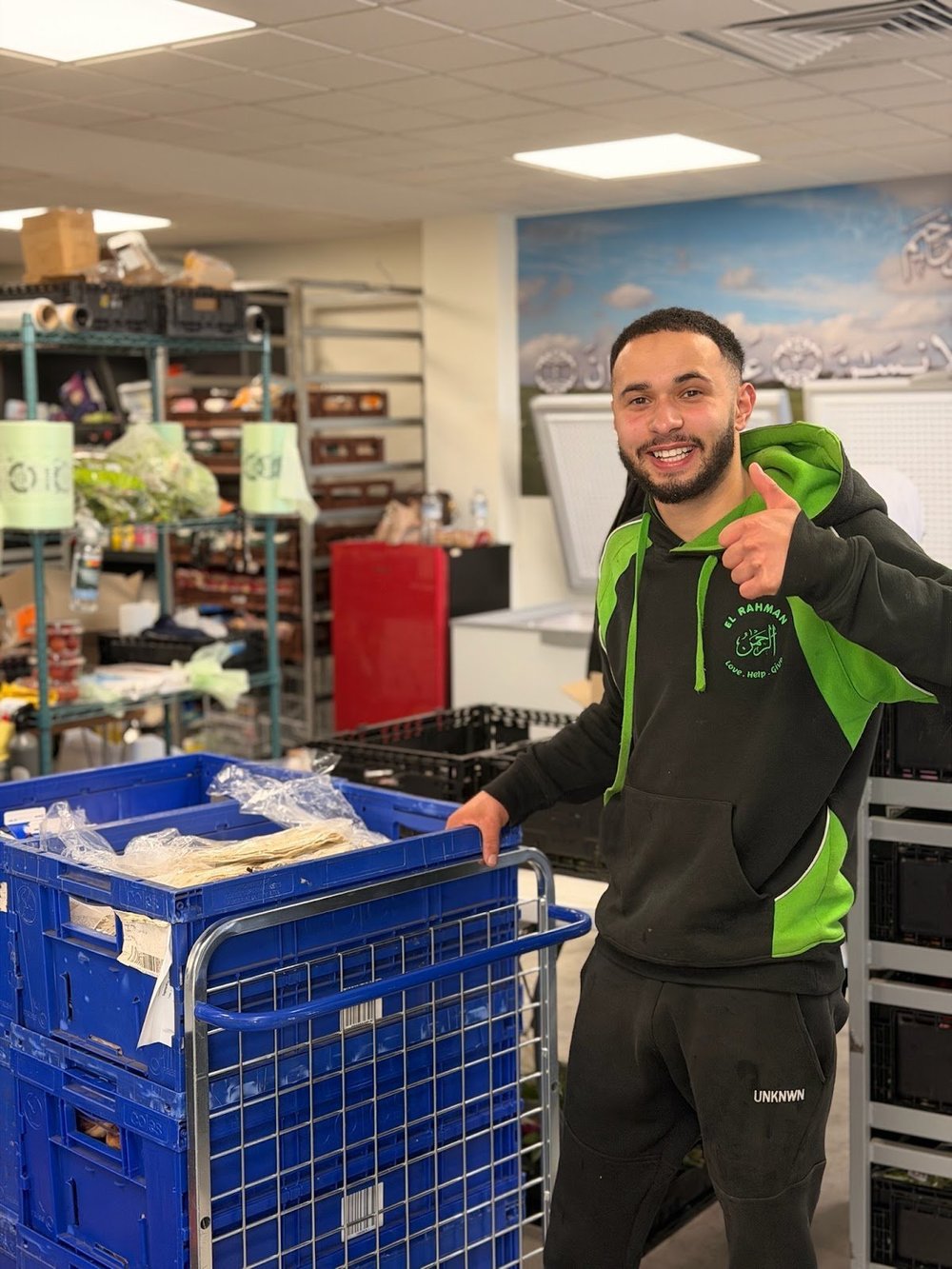 Smiling volunteer with a trolley of food crates