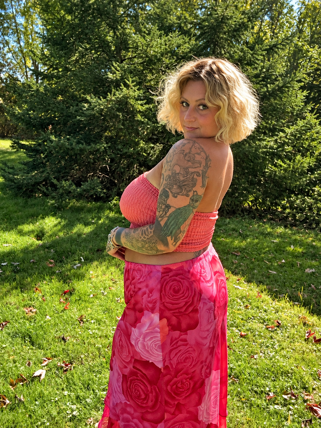 Bee in a pink floral skirt, looking over her shoulder in a sunlit garden.