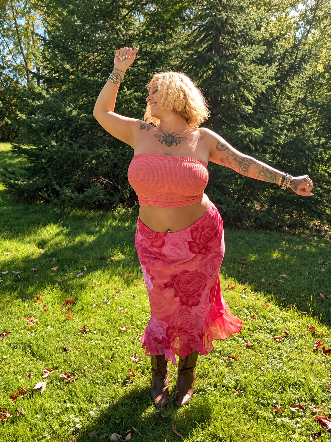Bee dancing freely outdoors in a coral top, rose print skirt and cowboy boots.