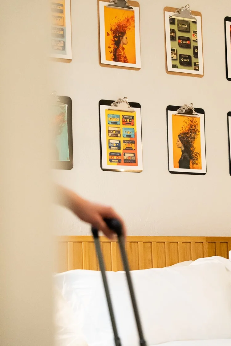 A guest rolling a suitcase past the art wall