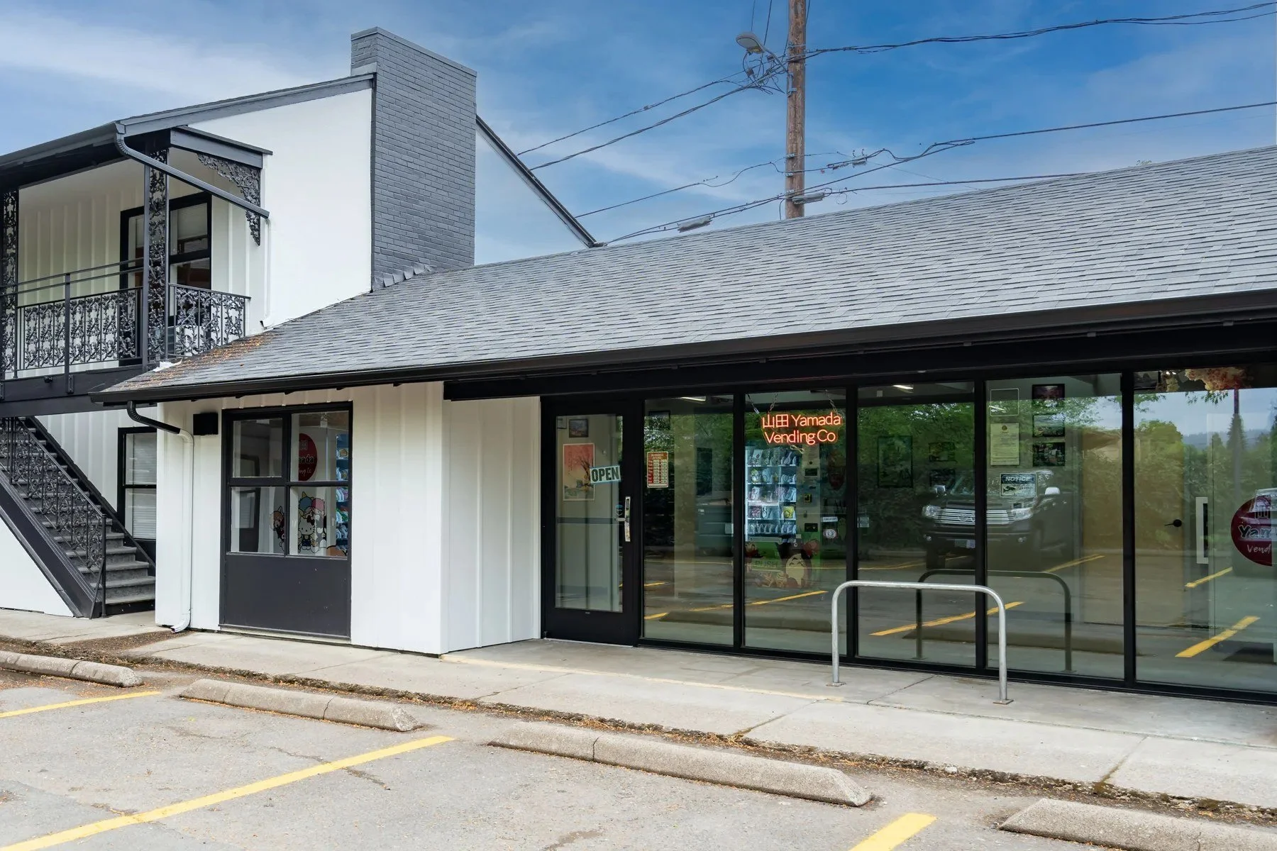 The shop wing at The Local Motel & Shops, with glass storefronts along the parking lot