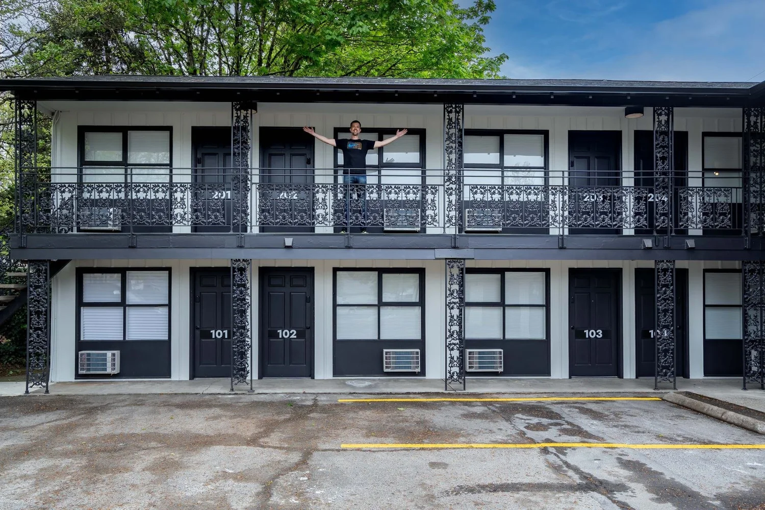 A guest with arms wide open on the motel's upper balcony
