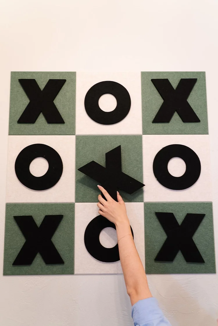 A hand playing the tic tac toe wall game