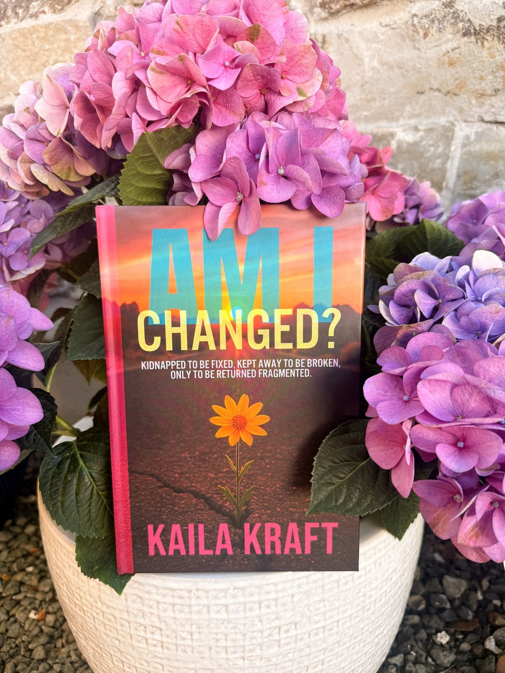 A copy of Am I Changed? tucked into a pot of hydrangeas