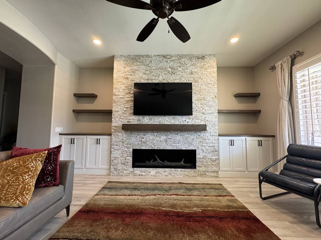 KBK light stone fireplace wall with floating shelves and white cabinets