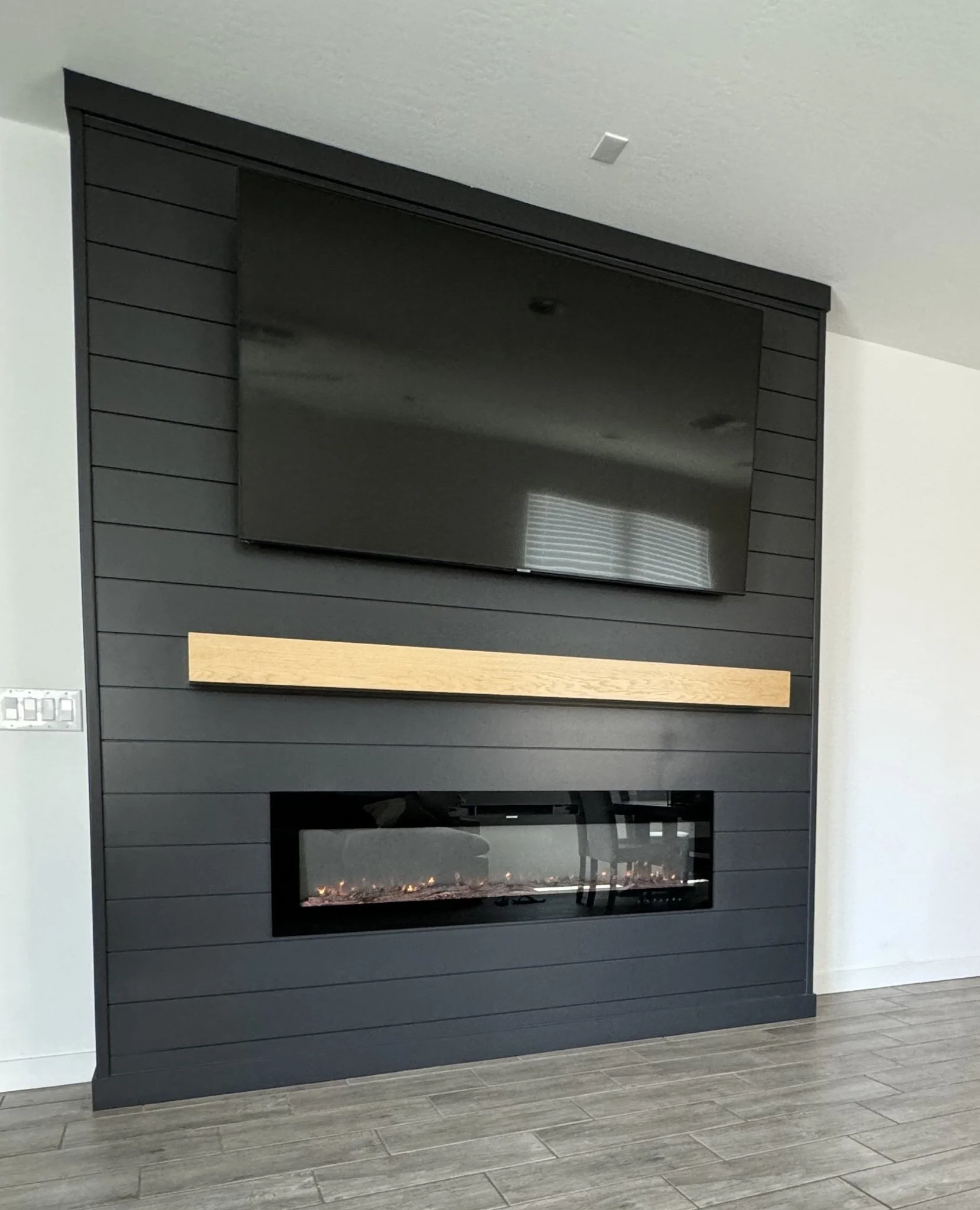 Black shiplap fireplace wall with a natural wood mantel