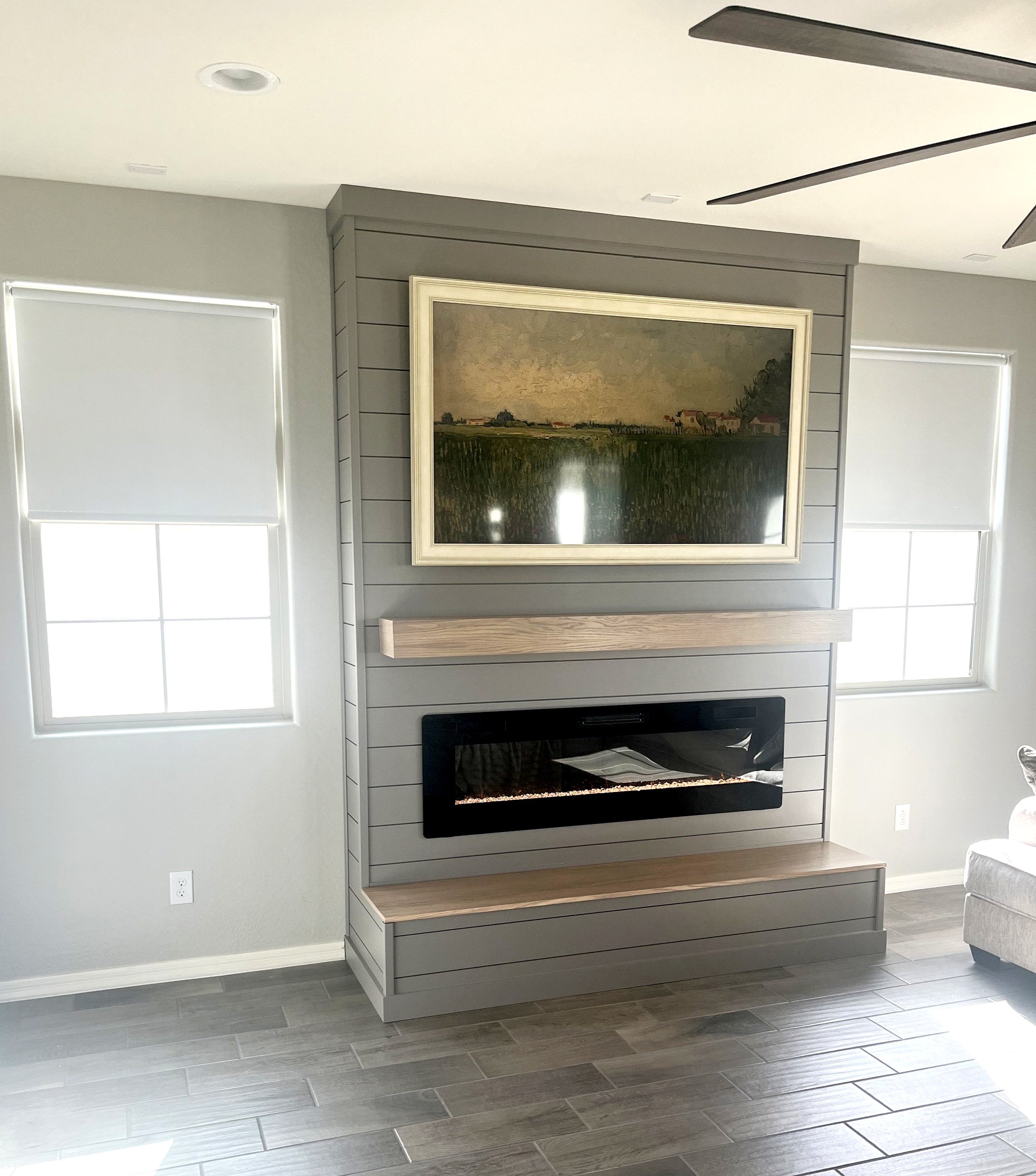 Gray shiplap fireplace wall with a wood mantel and raised hearth