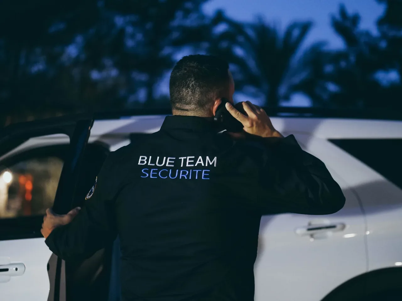 Un membre de BLUE TEAM au téléphone près d’un véhicule, à la tombée du jour.