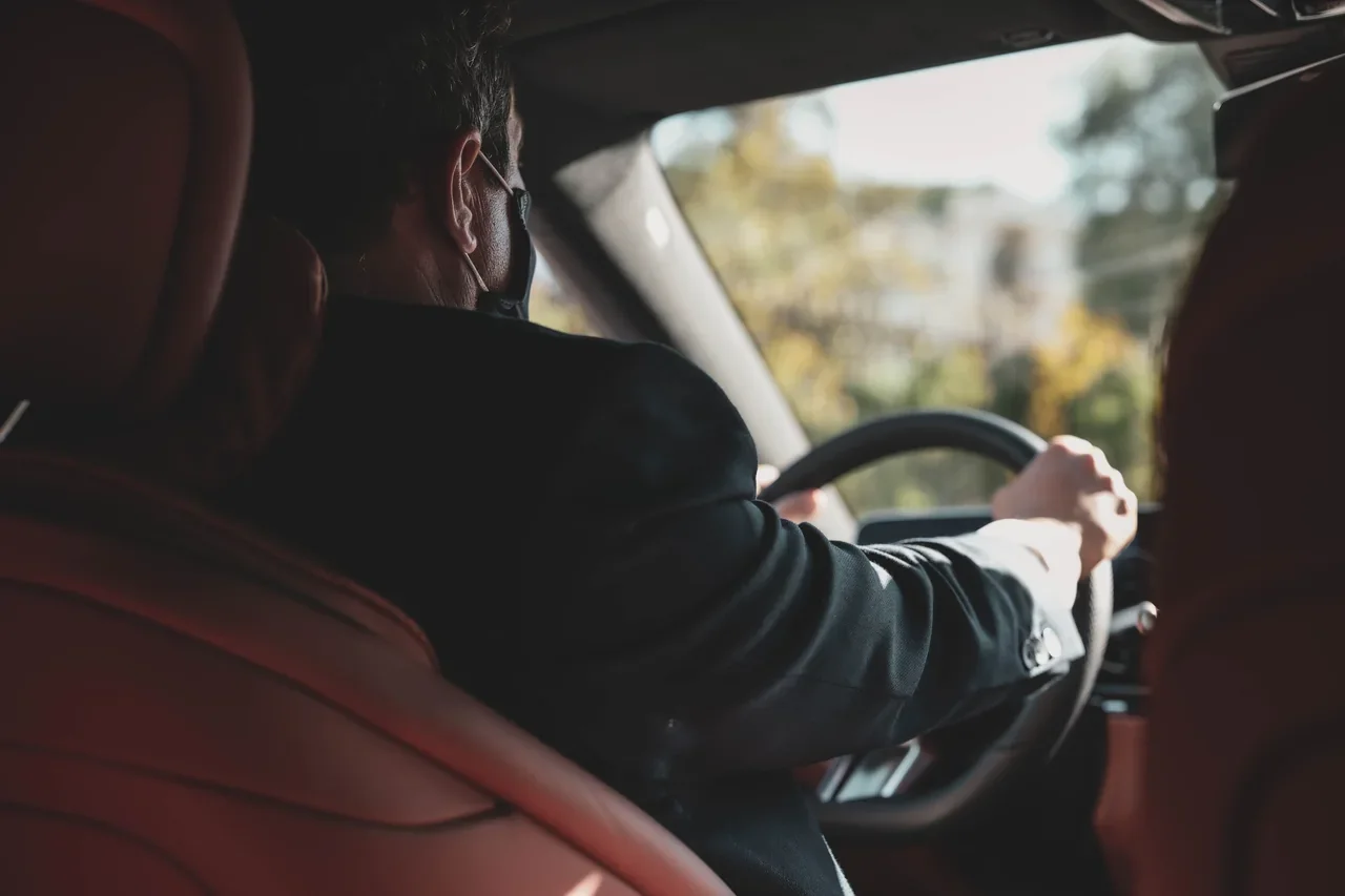 A chauffeur at the wheel, viewed from the rear seats.
