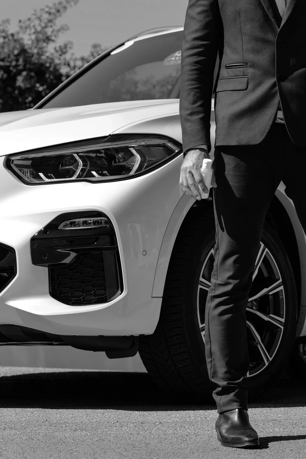 Un chauffeur en costume près d’un véhicule blanc.