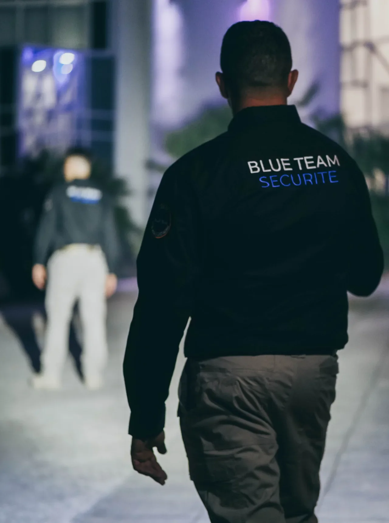Un membre de BLUE TEAM dans un espace extérieur éclairé en soirée.