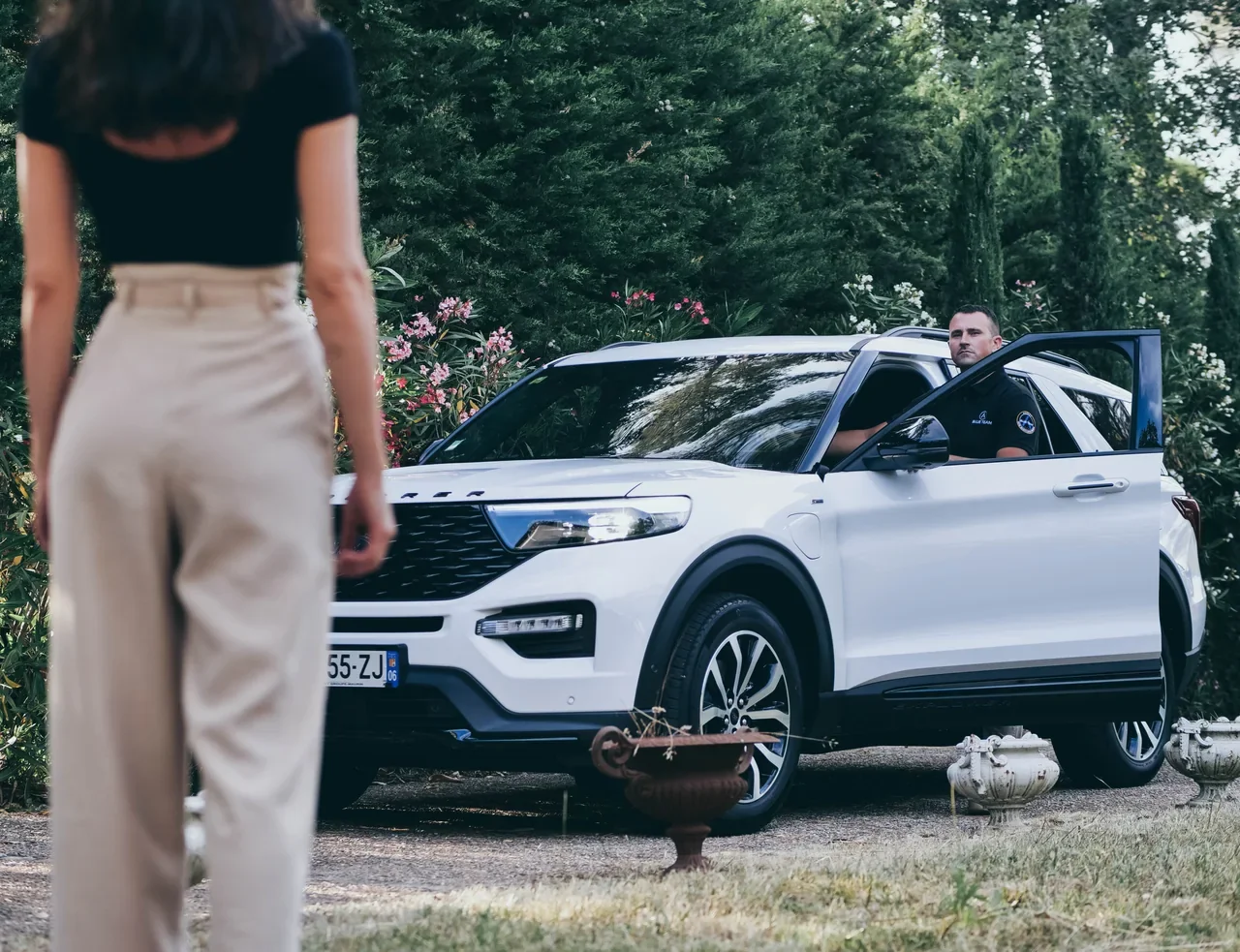 Un membre de BLUE TEAM près d’un véhicule dans un jardin résidentiel.