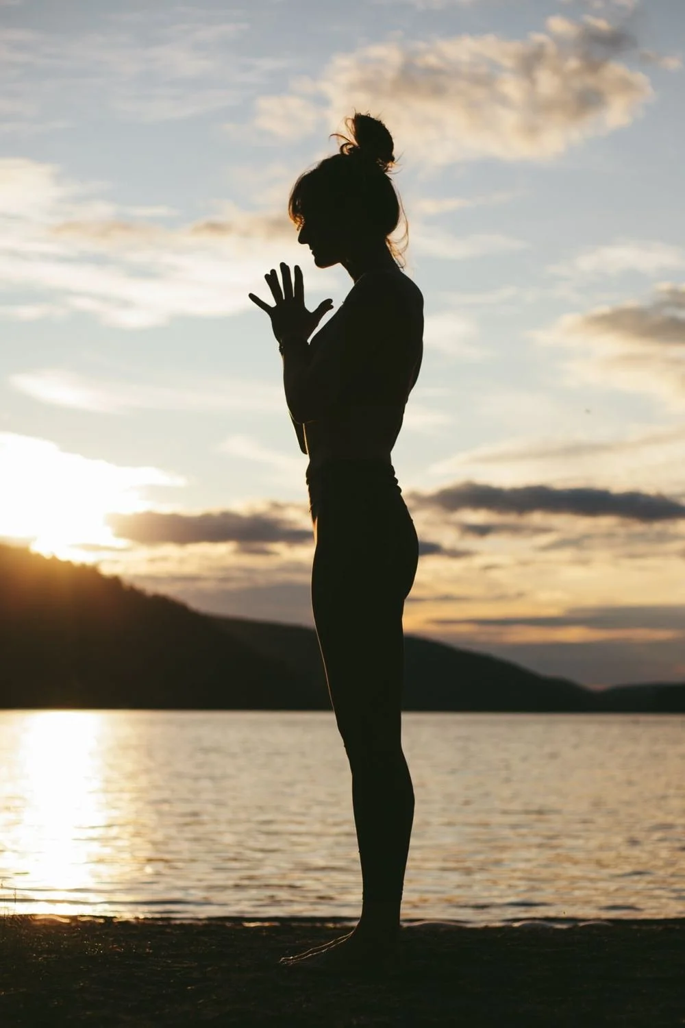 Standing silhouette in prayer by the water