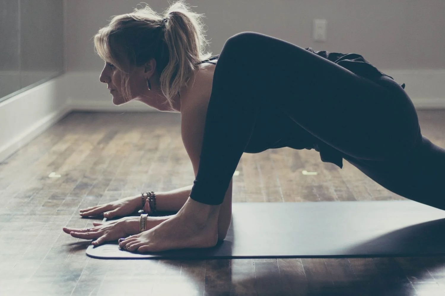 Genevieve moving low to the mat in a sunlit studio