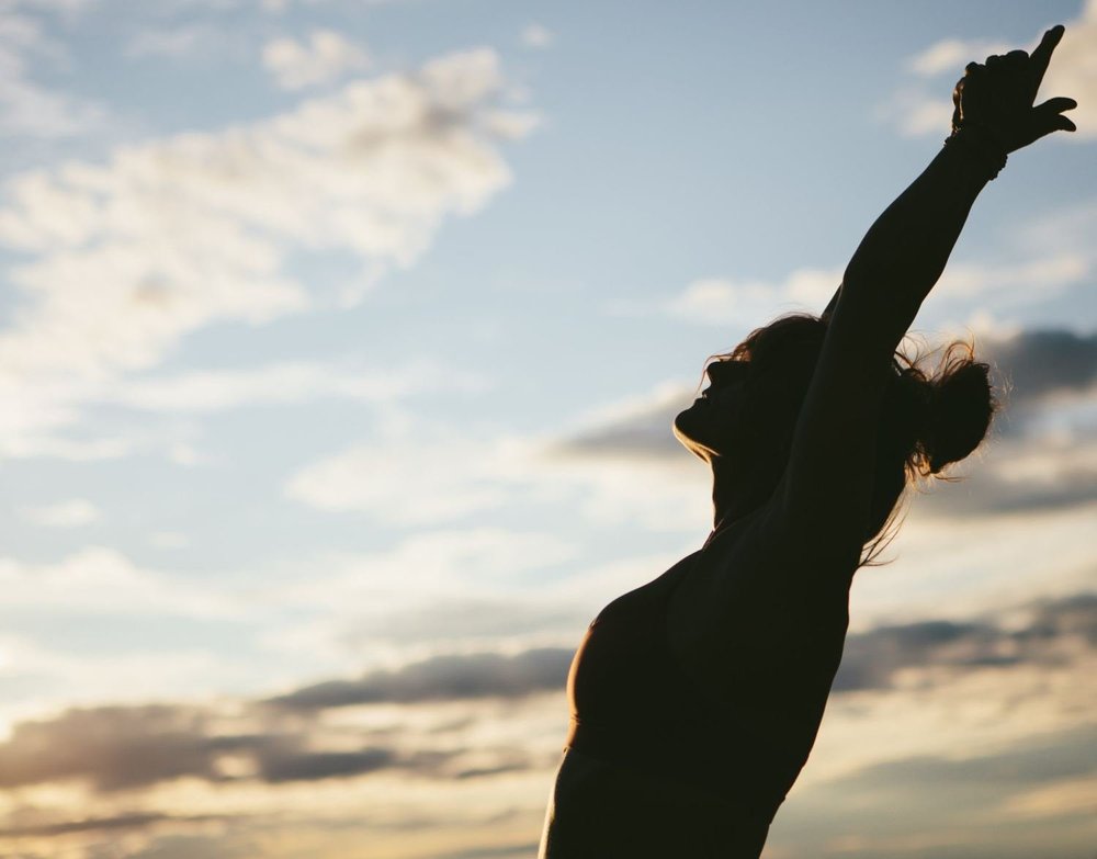 Silhouette reaching toward an open sky