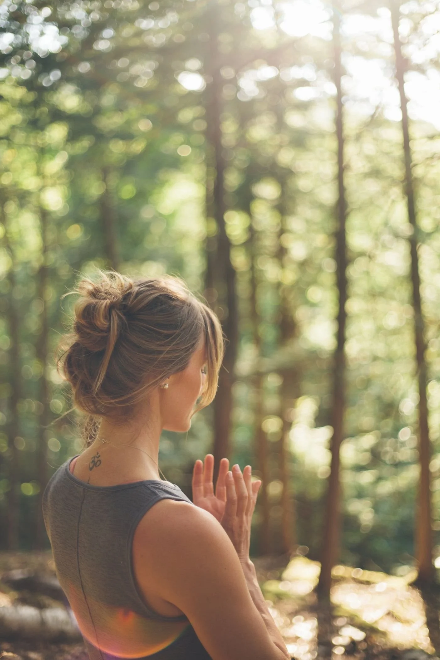Genevieve with hands at her heart, facing a sunlit forest