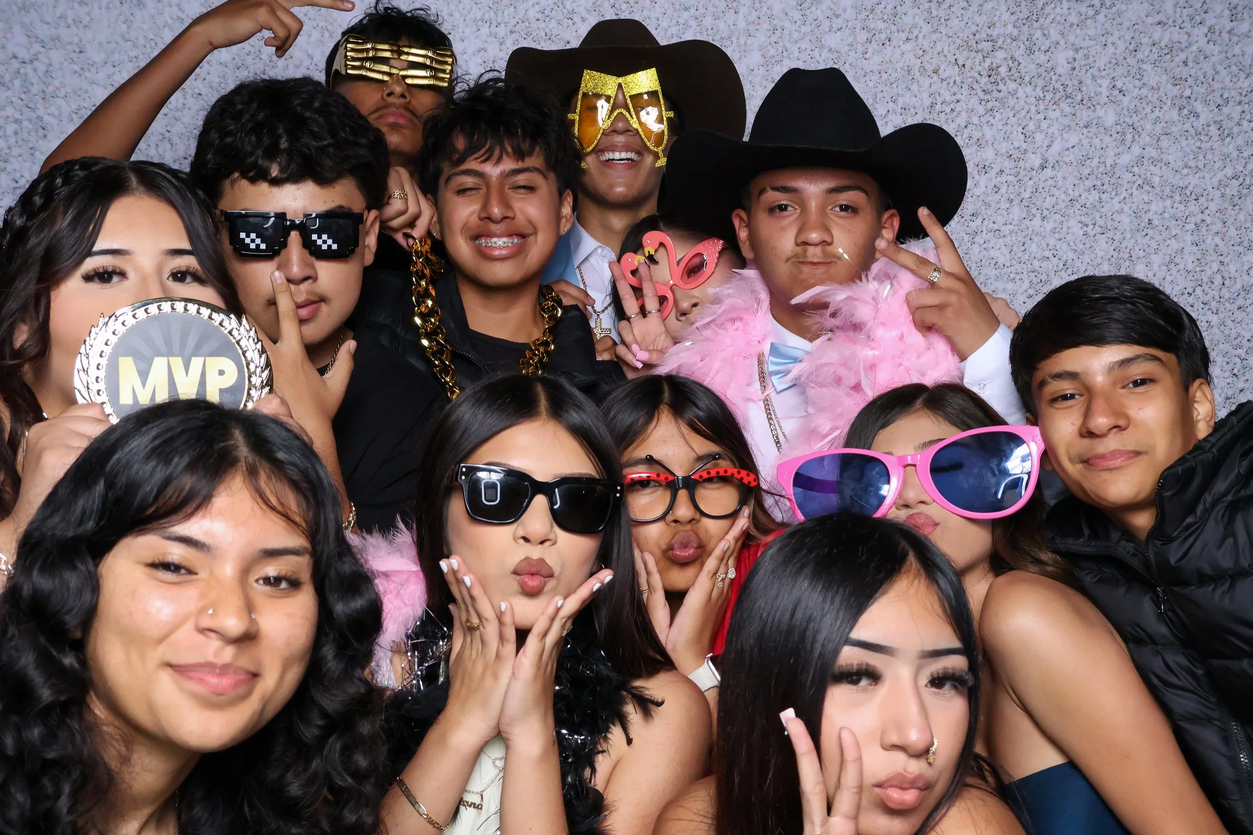 Large group of friends with colorful photo booth props against a silver backdrop