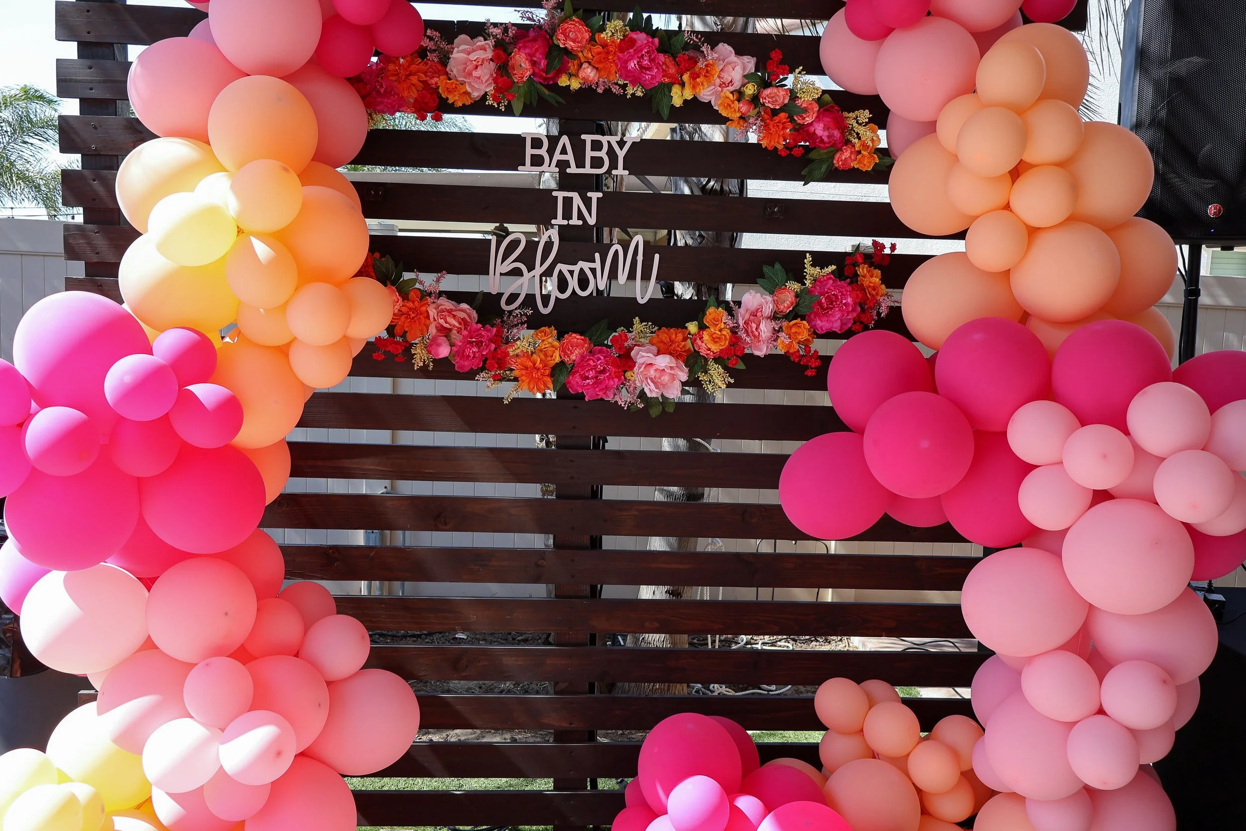 Baby in Bloom backdrop decorated with flowers and pink and peach balloons