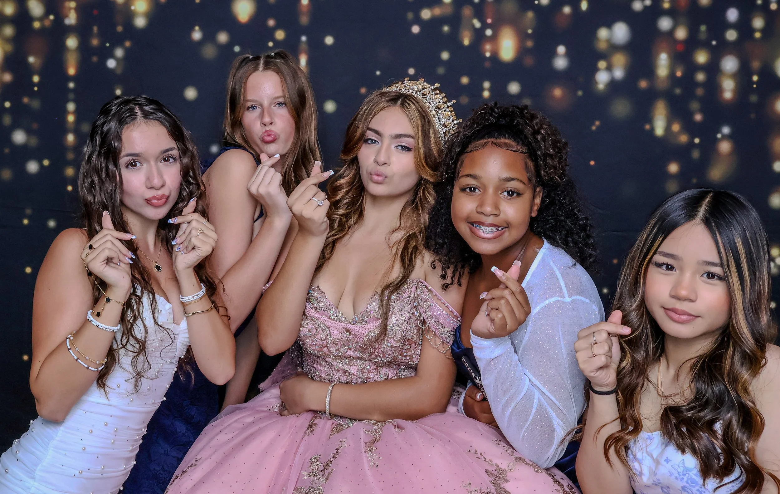 Quinceañera guests posing together in formal dresses at the open-air photo booth