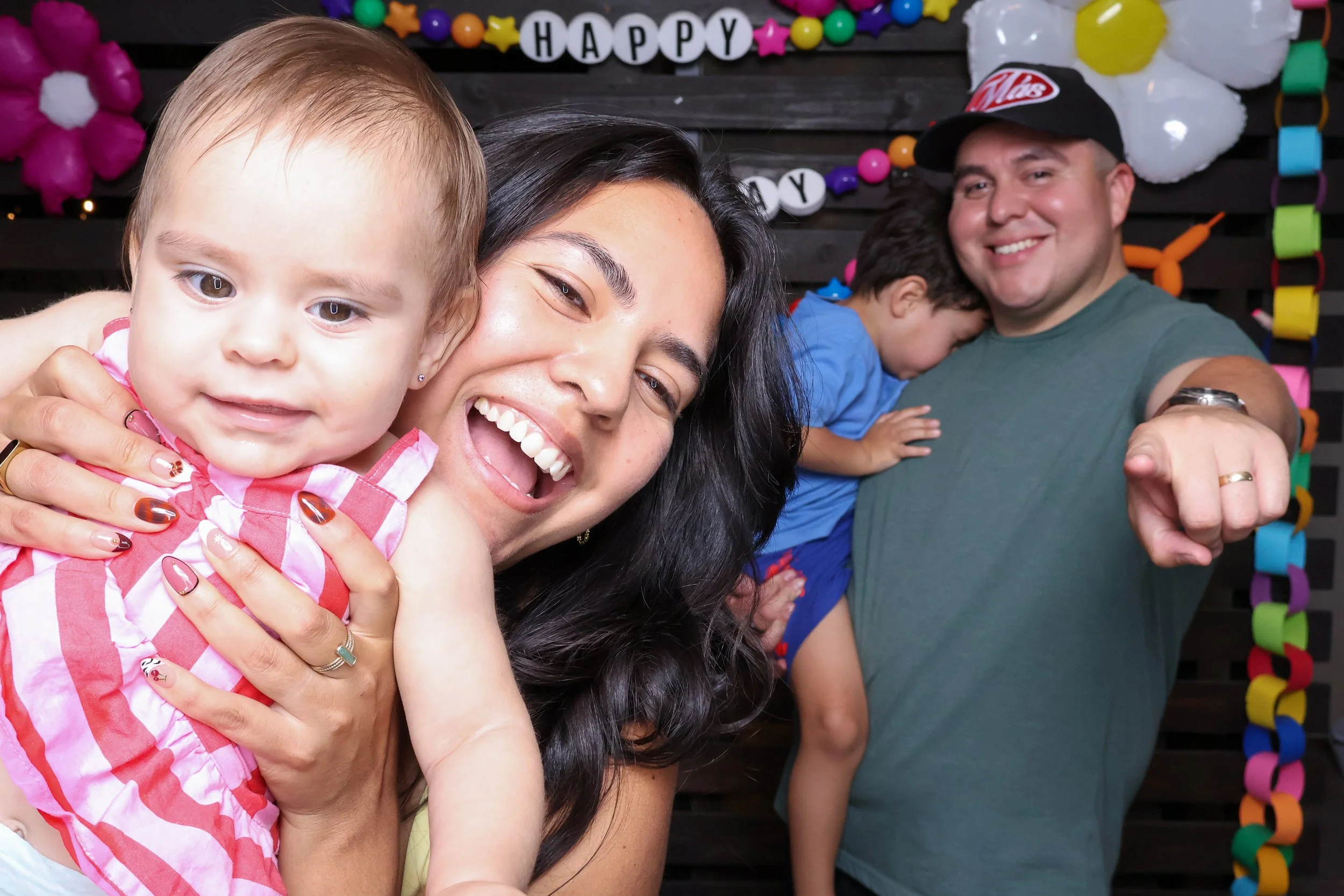 Family smiling and posing together at a colorful birthday photo booth