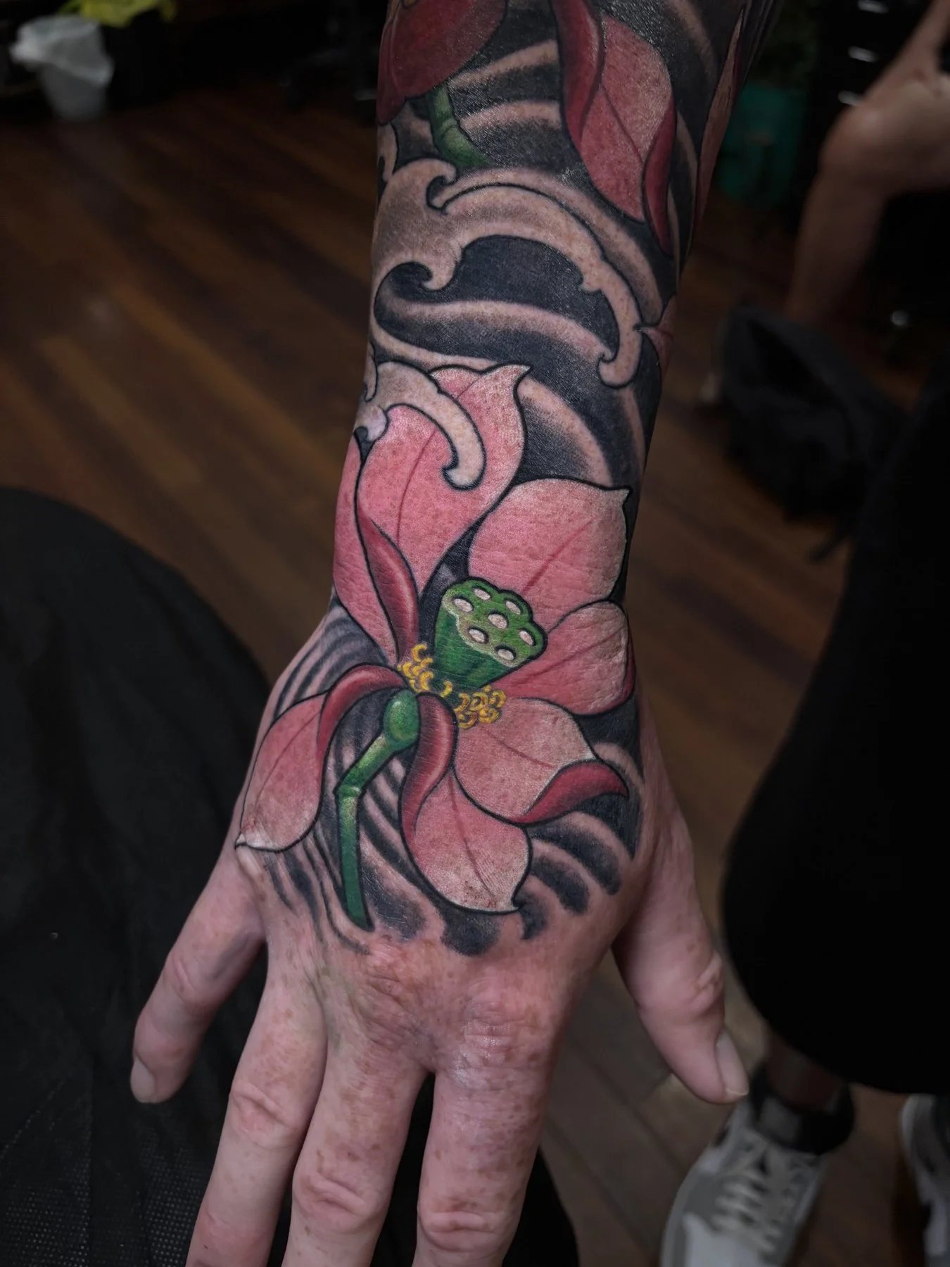 Finished pink lotus tattoo extending onto Wade’s hand