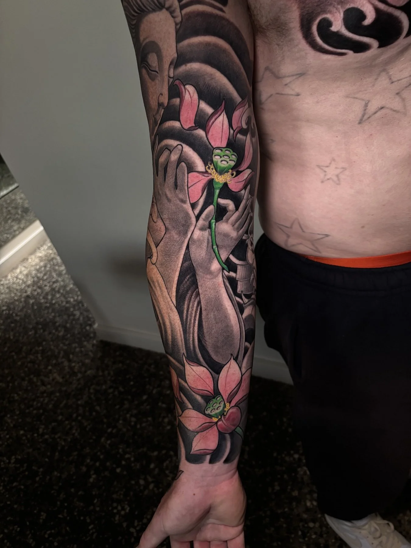Finished inner arm detail with hands holding a pink lotus flower