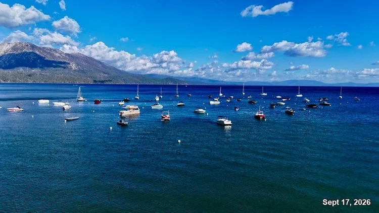 Sailboats and motorboats moored on blue Lake Tahoe, with mountains and white clouds beyond. Date: Sept 17, 2026.