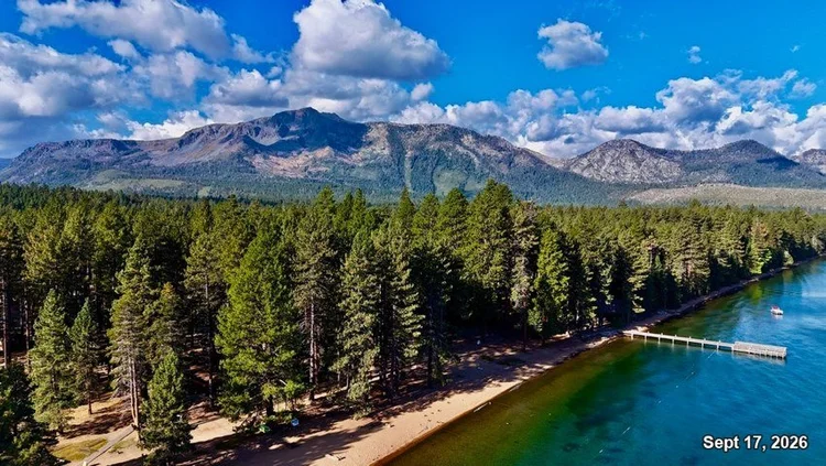 Lake Tahoe's turquoise shoreline, sandy beach and white pier beneath pine forest and a mountain ridge. Date: Sept 17, 2026.