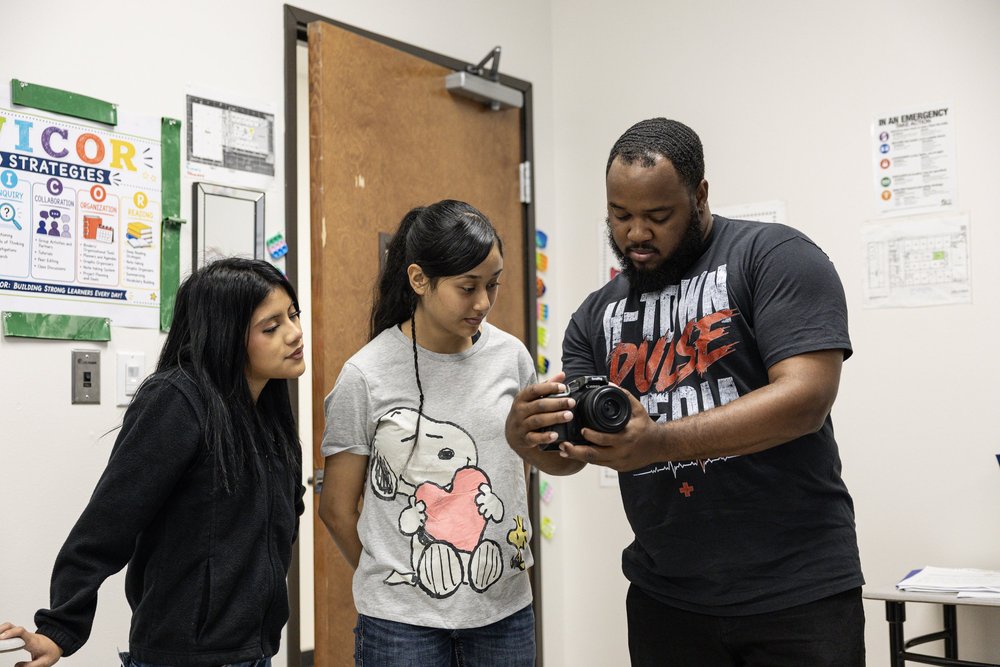 HTP photographer demonstrating a camera to two students