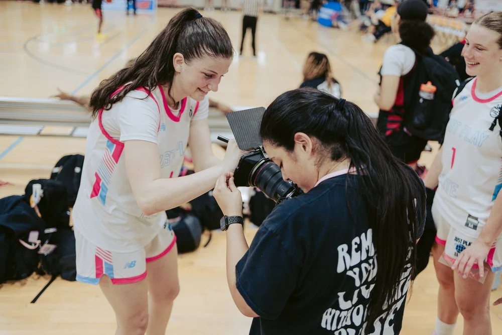 Photographer and basketball player reviewing a camera courtside