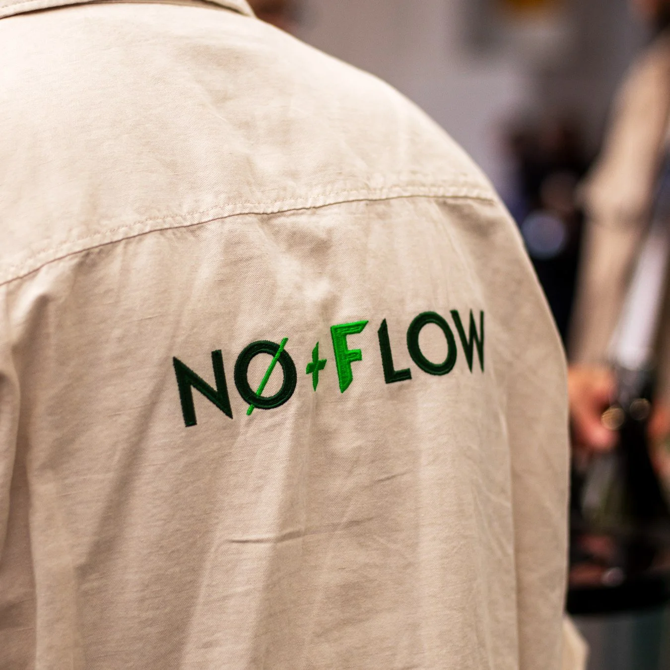 Close-up of the embroidered No+Flow logo on a shirt
