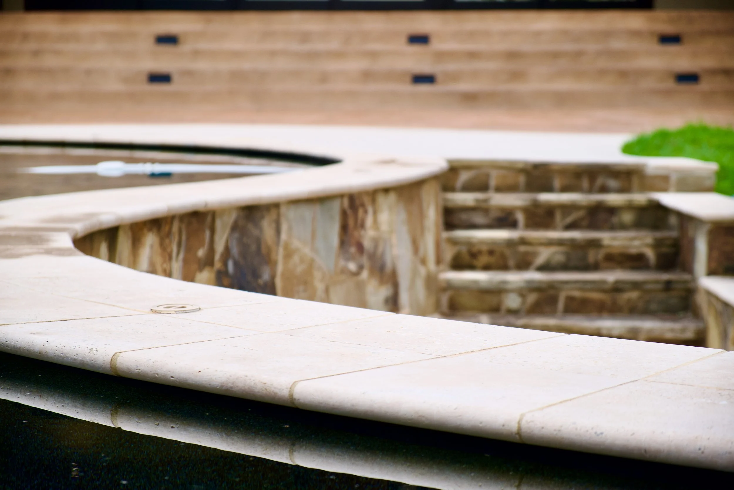 Detail of refinished pool-deck stone coping with Cool Deck surface treatment