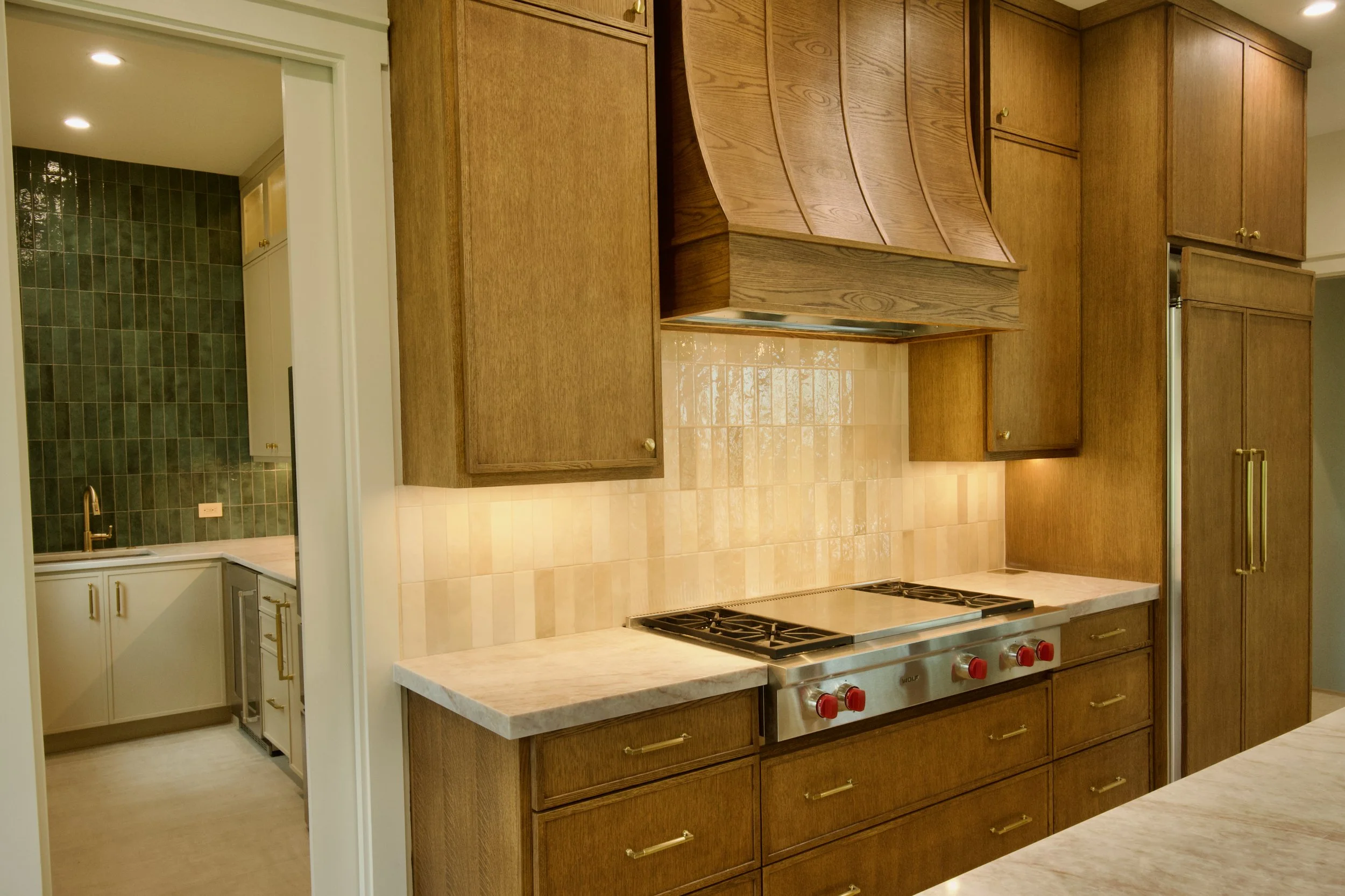Custom white oak vent hood over Wolf range with zellige tile backsplash