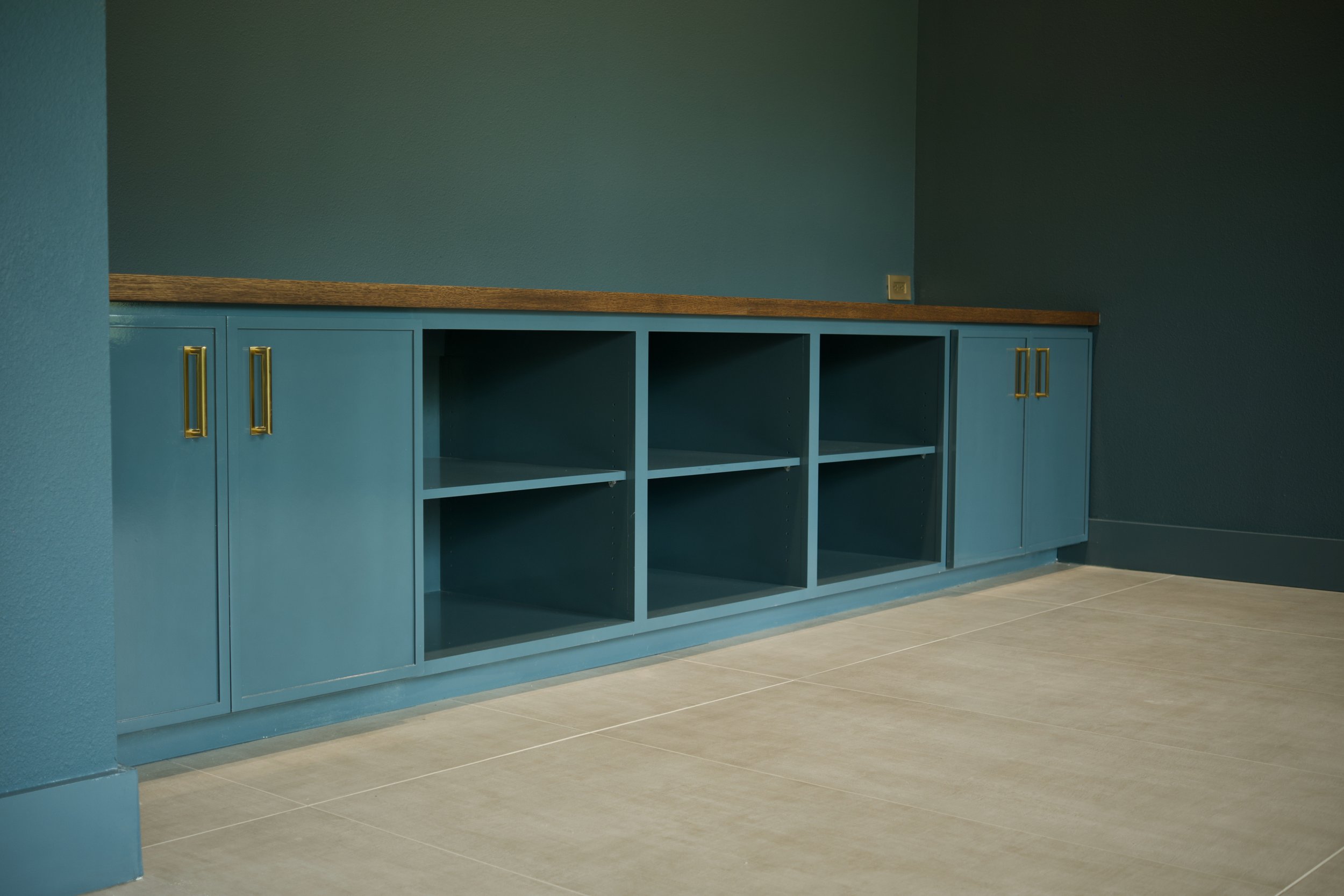 Private study with custom blue walls and built-in cabinetry behind sliding glass pocket doors