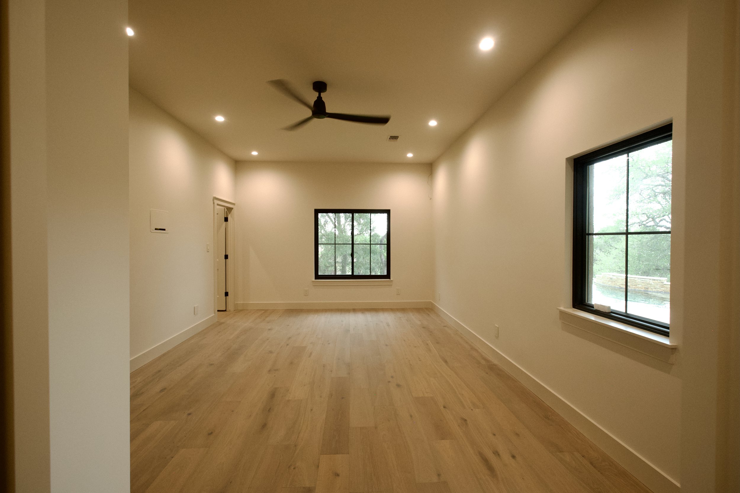 Expanded media room with symmetric windows and light hardwood flooring