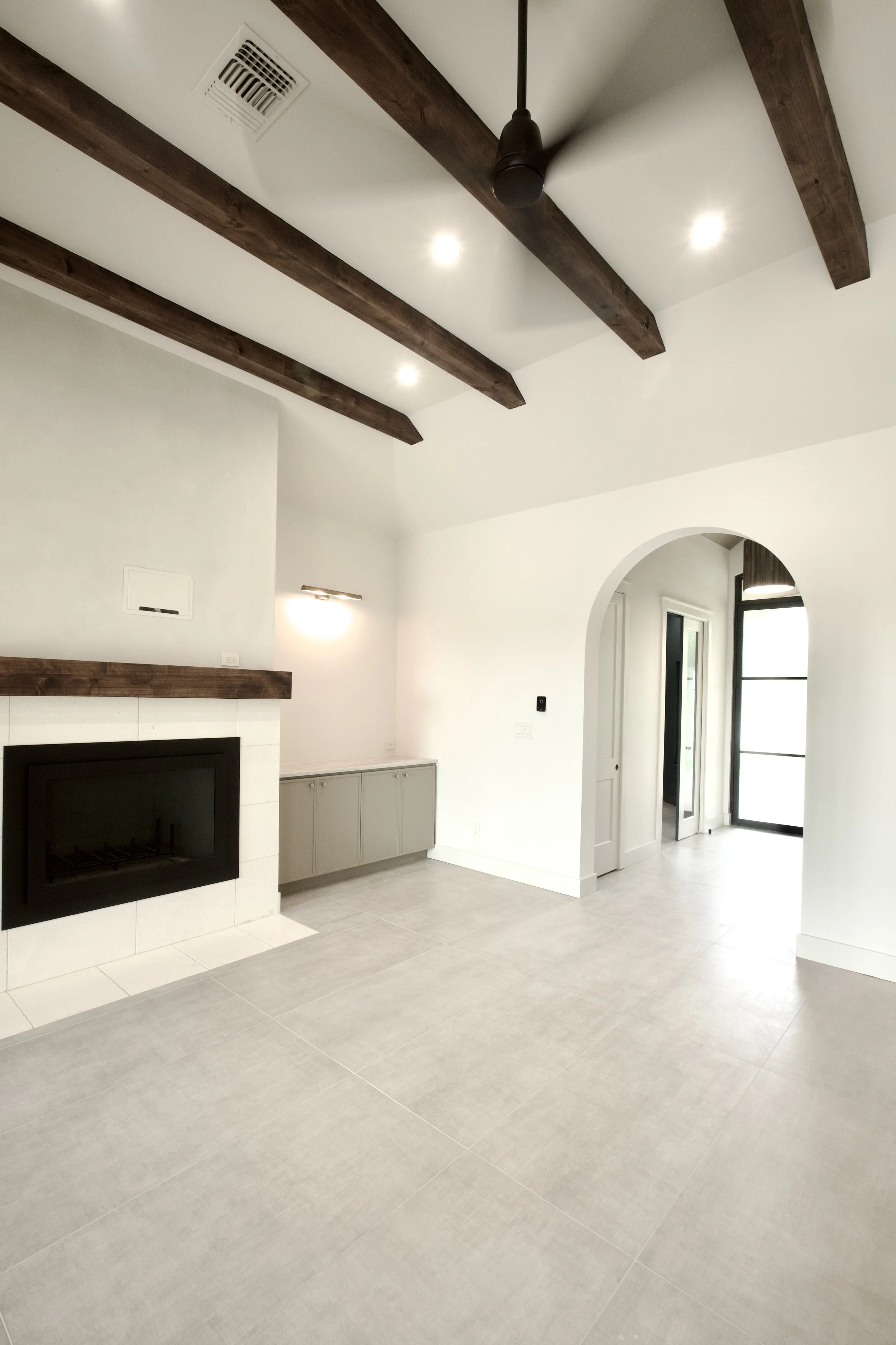 Main living area with redesigned fireplace, stained decorative beams, floating mantel, and custom built-in cabinetry