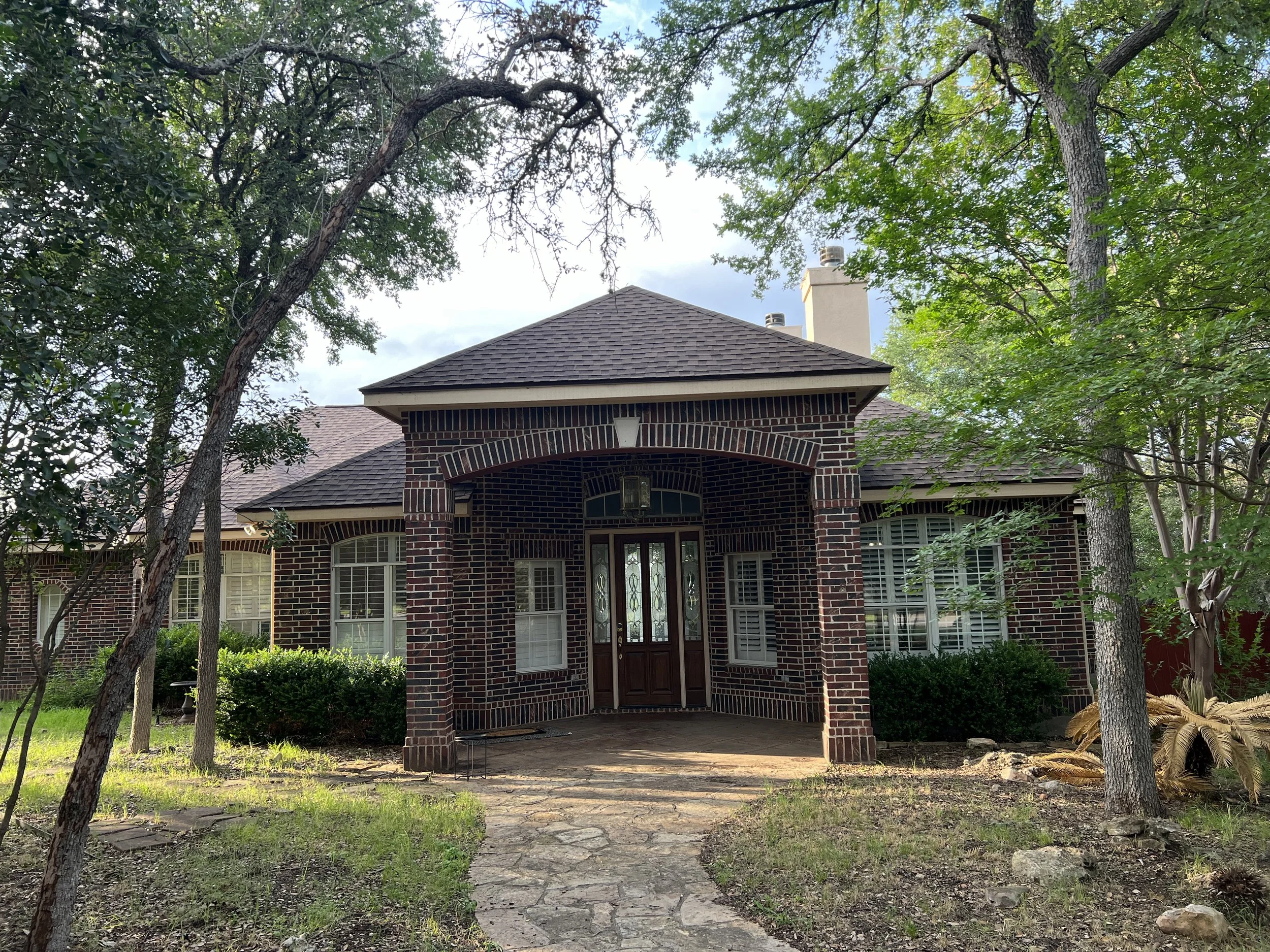Original dark red brick front facade with arched portico before renovation