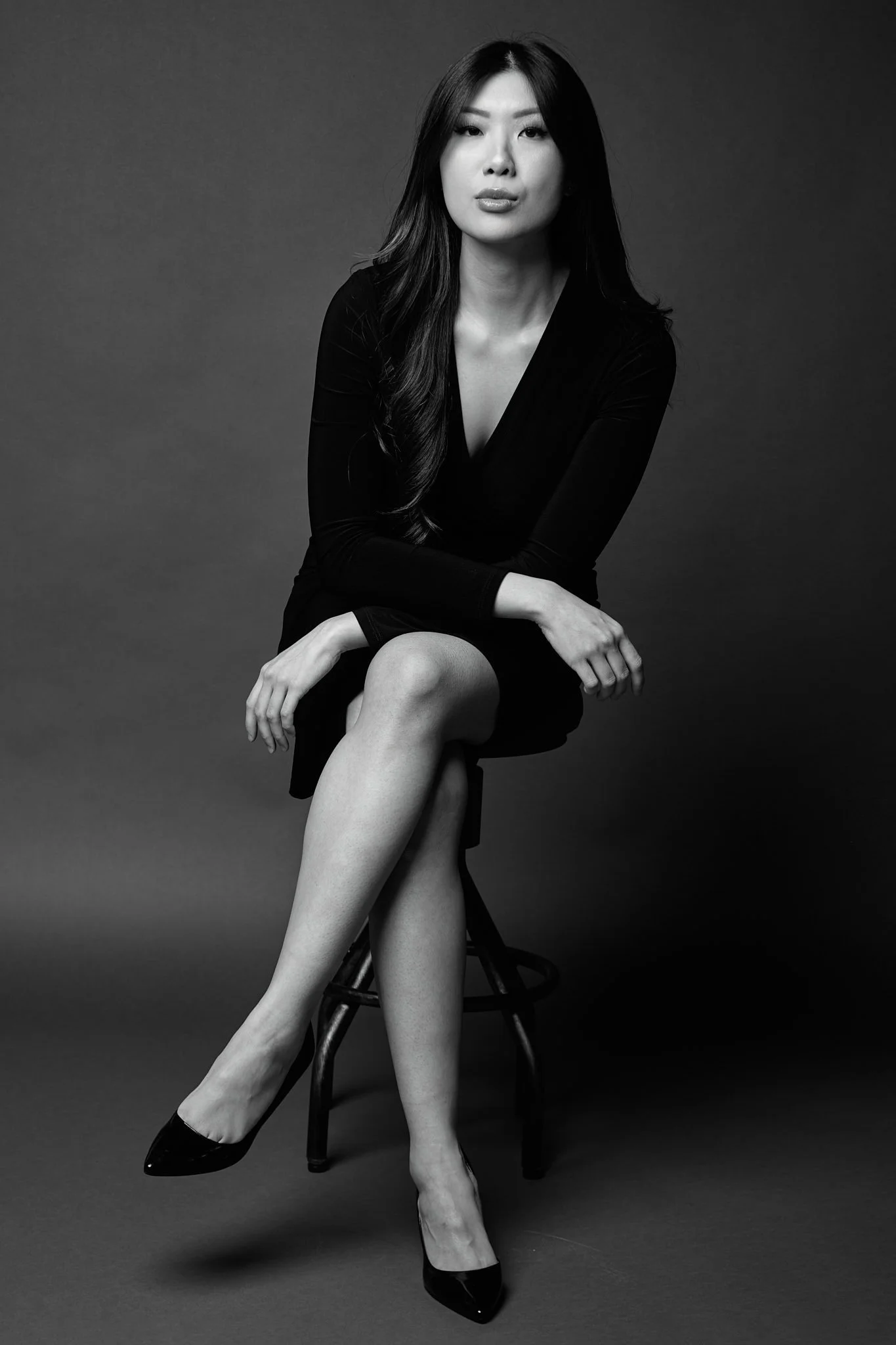 Black and white full-length portrait of a woman seated on a stool