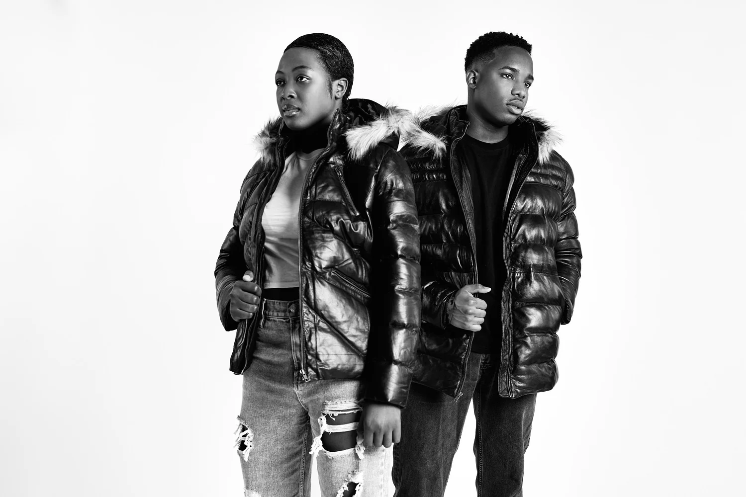 Two models in glossy puffer jackets with fur hoods for FAD Closet, on a white studio background, black and white
