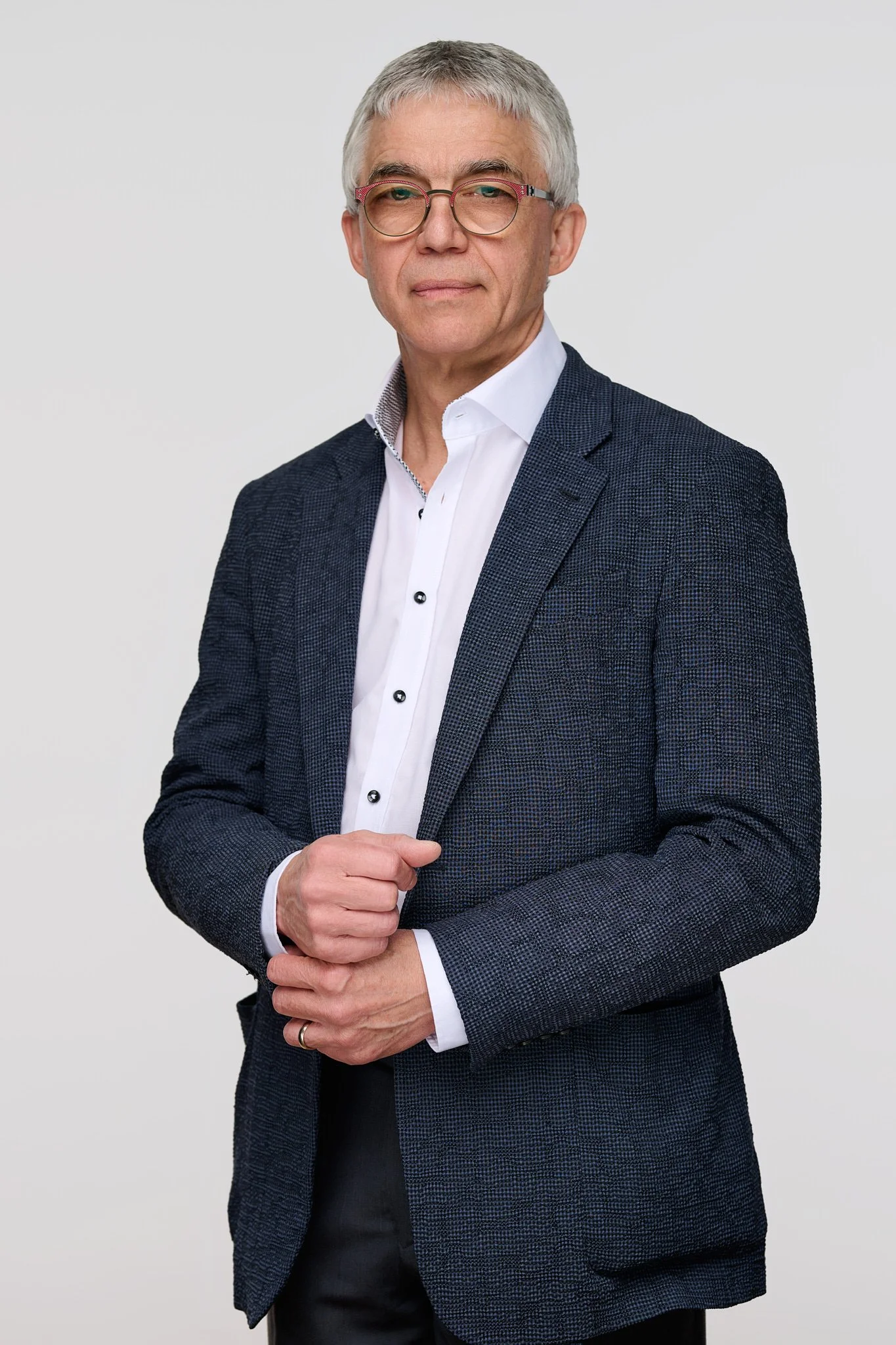 Color portrait of a man in glasses and a navy jacket on a light ground