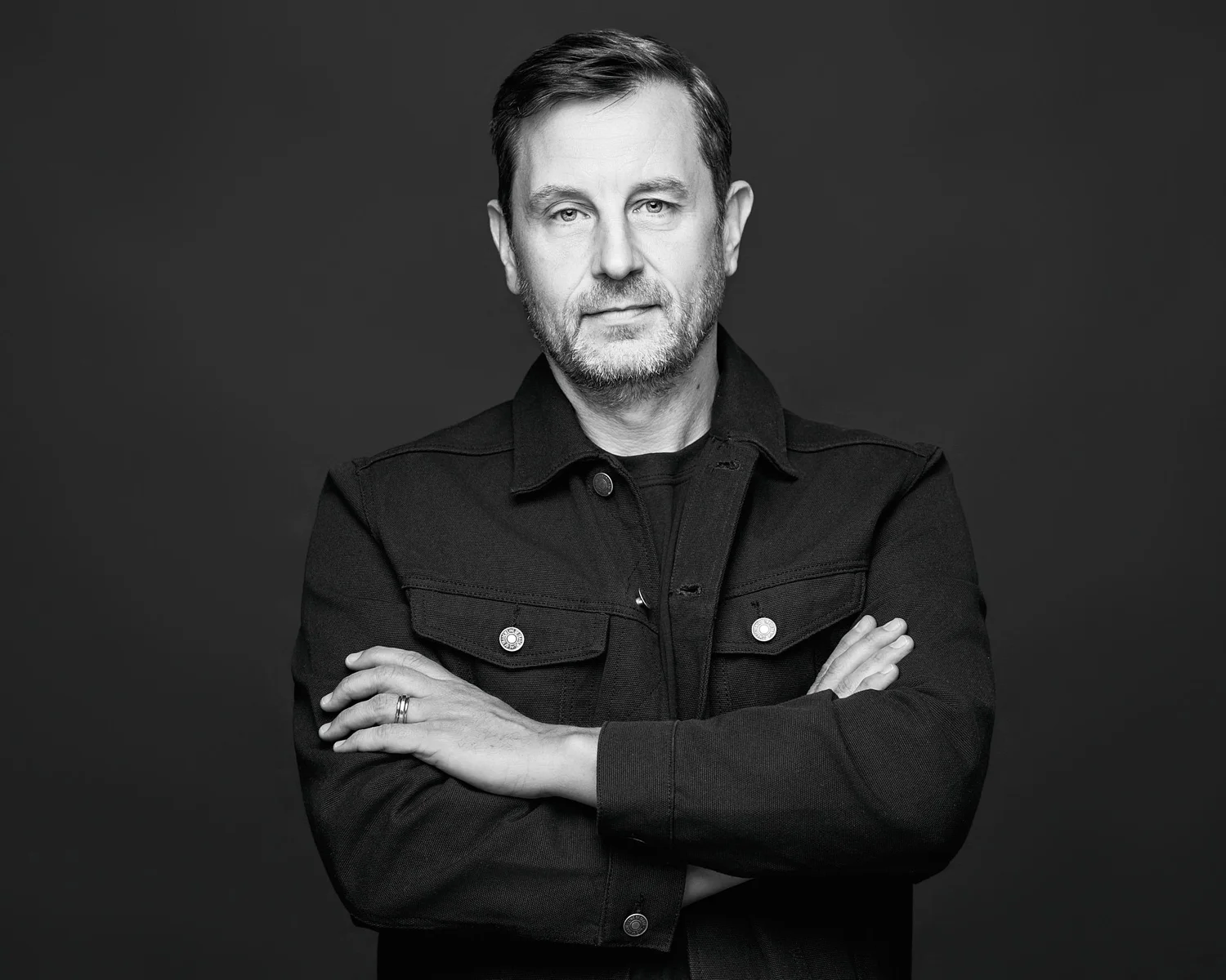 One of the owners of Koopers Whiskey, arms crossed, black and white studio portrait on a dark backdrop