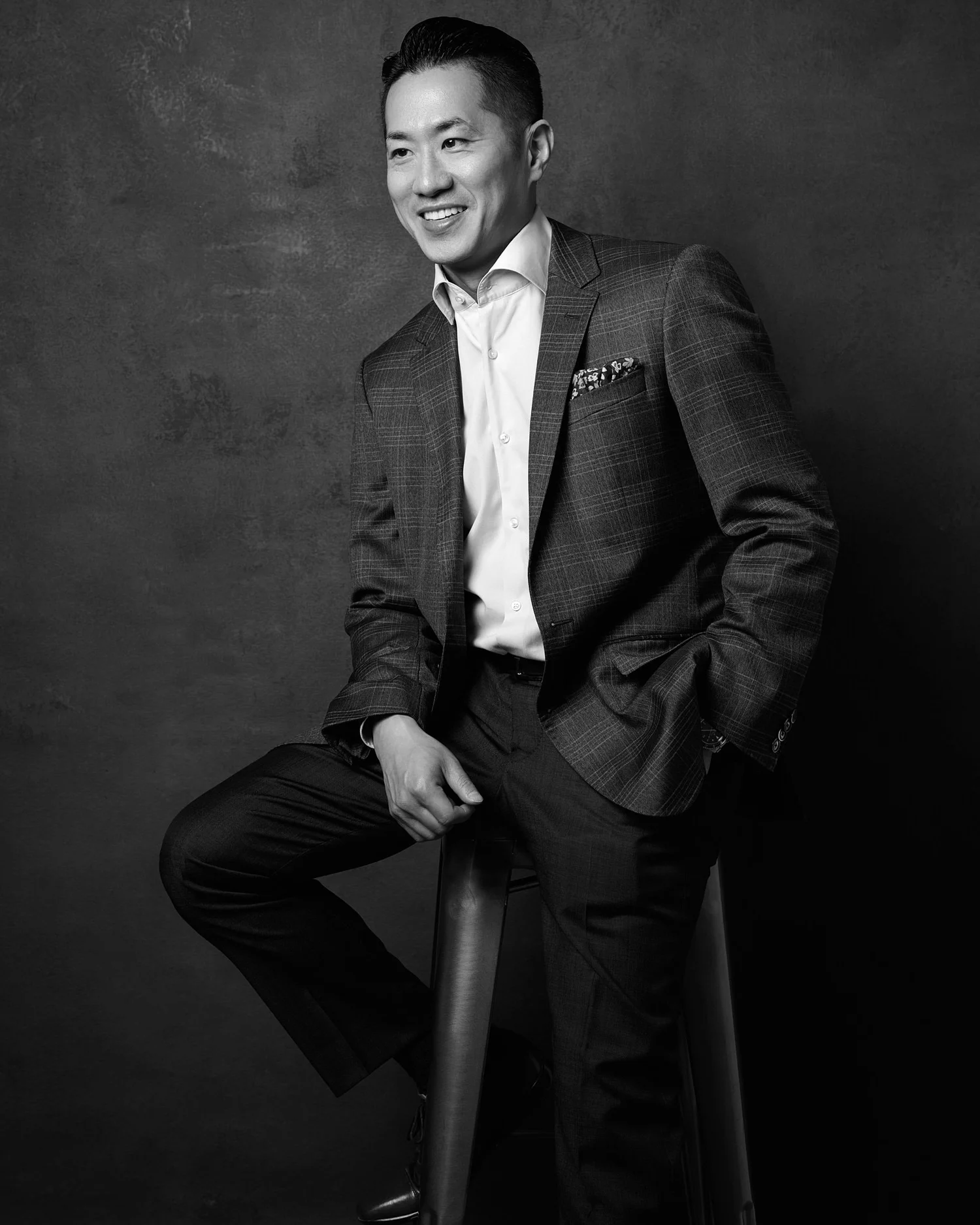 Black and white portrait of a man in a suit seated on a stool, photographed by Ryan Dunbar